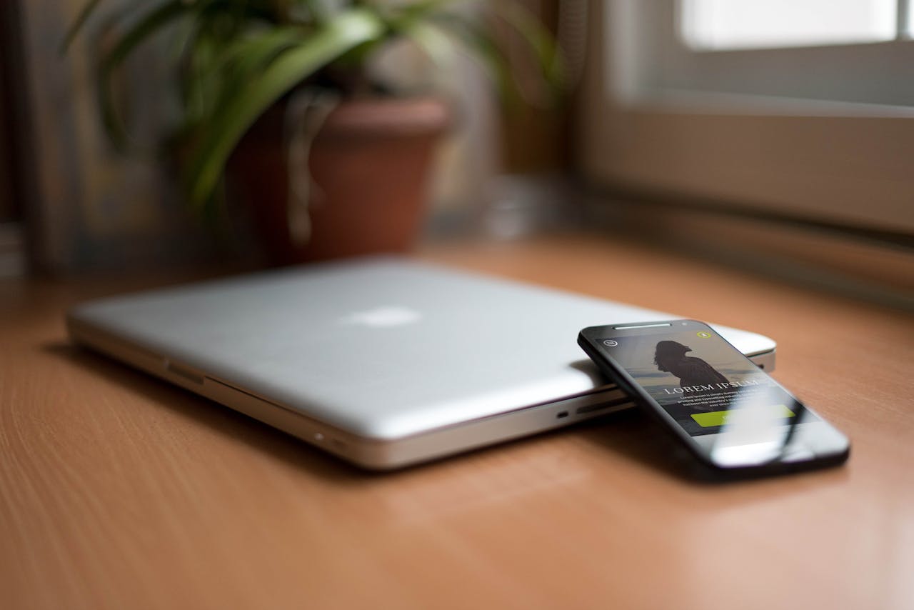Services Close-up of a silver laptop and smartphone on a wooden desk, capturing modern work essentials.