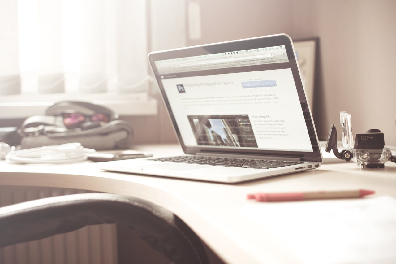 A clean and bright workspace featuring a laptop open on a wooden desk, highlighting a typical tech environment.
