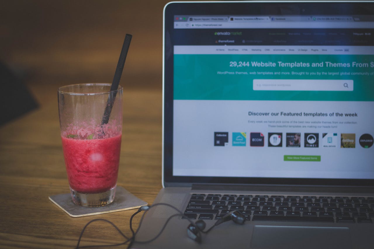 About A fruit shake on a desk next to a laptop displaying a website, blending work and refreshment.
